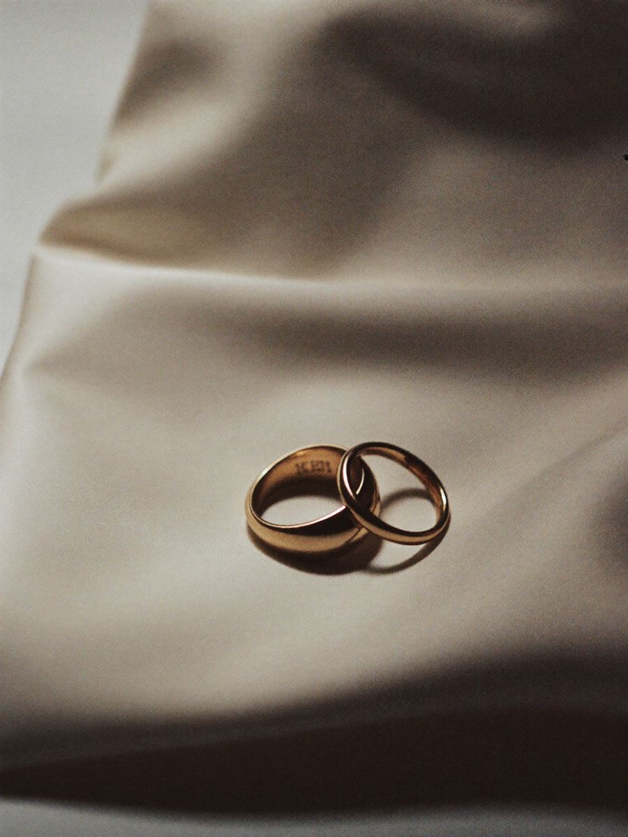 Two wedding rings resting on folded raw silk in soft window light.